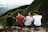 row of four men sitting on mountain trail