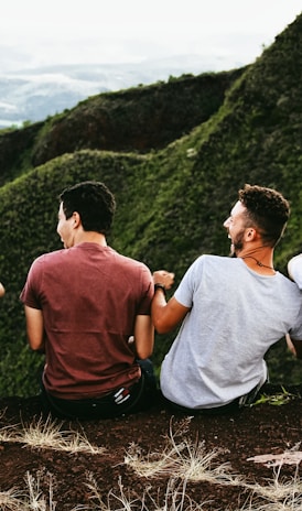 row of four men sitting on mountain trail