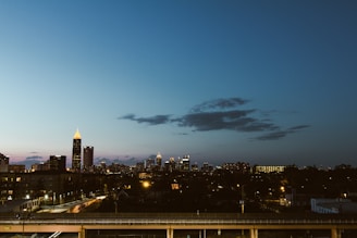 A city skyline at dusk with office buildings lit up.