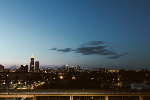 A city skyline at dusk with illuminated buildings and network cables.