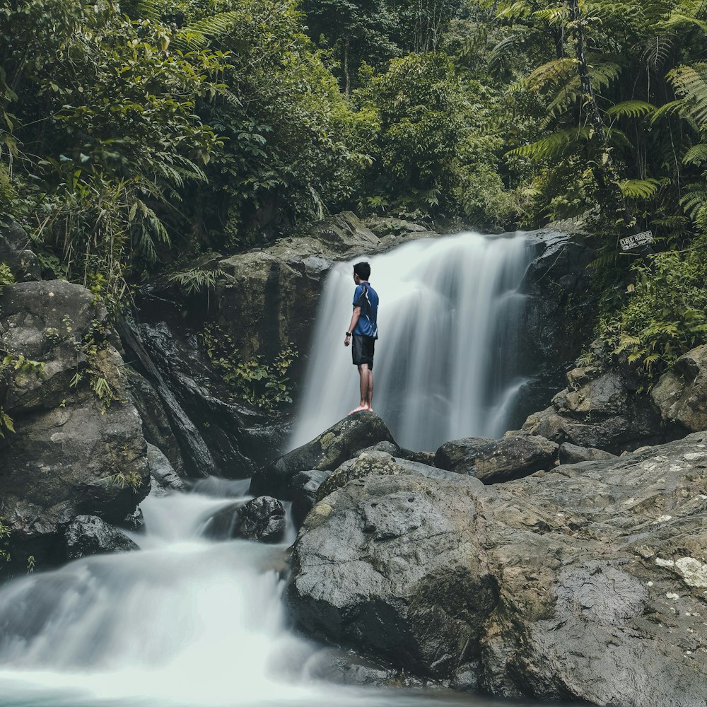 man standing on rocks with waterfalls background