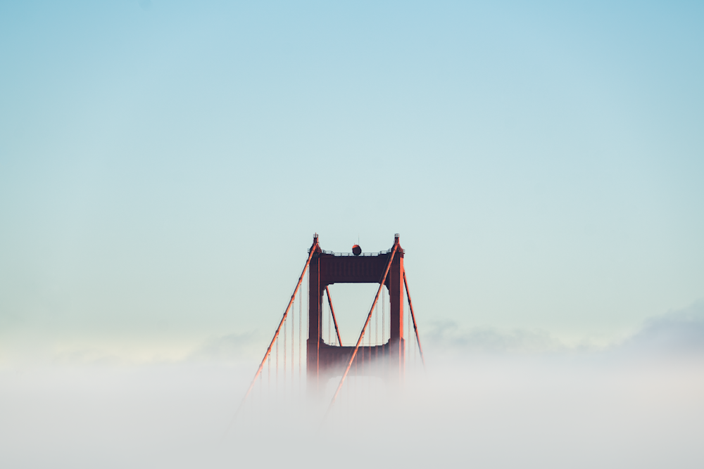 red concrete bridge surrounded by clouds