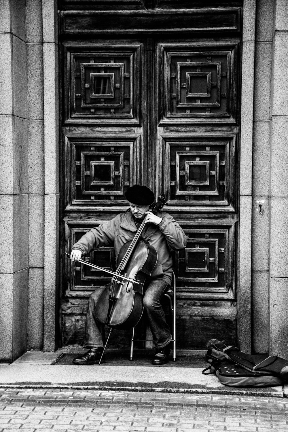 Black and white shot of street musician performing with cello in doorway in Riga