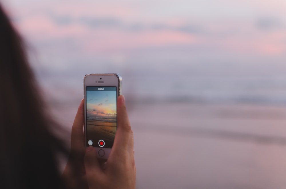 person taking a photo of of open sea and sunset