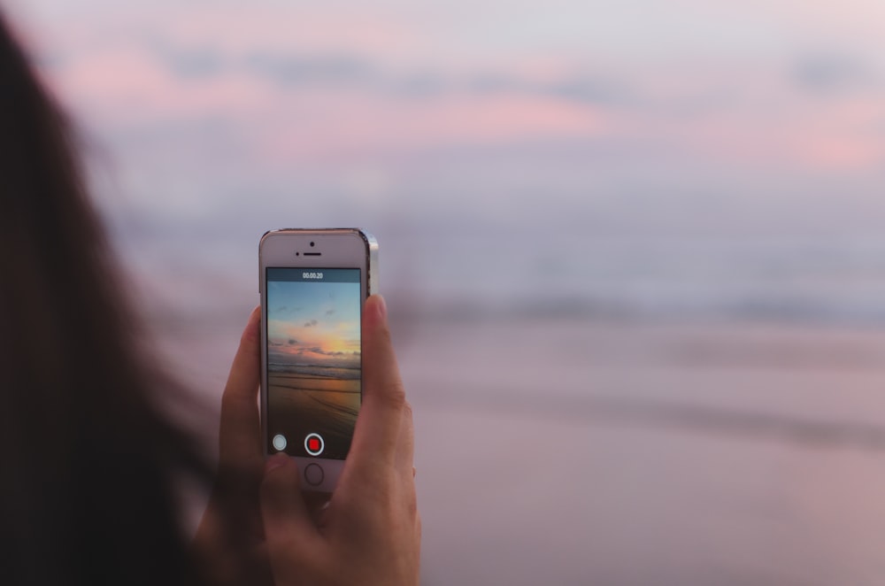 personne prenant une photo de la mer ouverte et du coucher du soleil