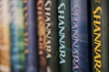 Several books are lined up vertically, with the spines displaying the word 'Shannara' in large letters. The spines are in different colors and textures, creating a visually appealing pattern.