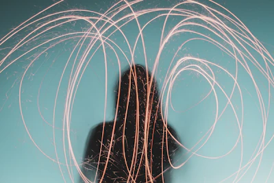 A silhouette of a person meditating with neon purple and green light trails swirling around.