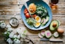 poached egg with vegetables and tomatoes on blue plate