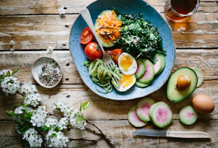 poached egg with vegetables and tomatoes on blue plate