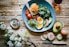poached egg with vegetables and tomatoes on blue plate