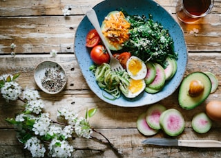 poached egg with vegetables and tomatoes on blue plate