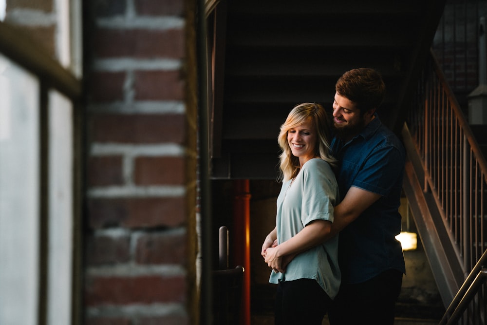 man hugging woman from behind near stair