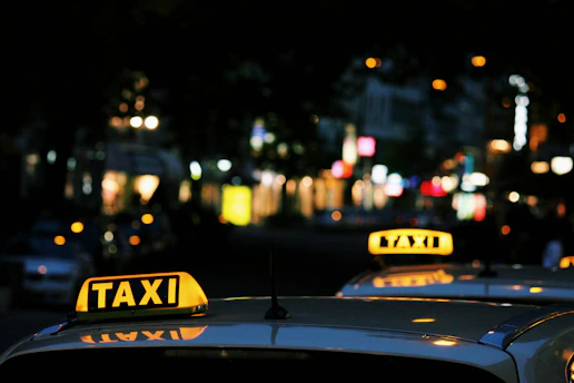A taxi driving through Kuwait city streets during the day with clear signage