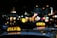 Brightly lit taxi signs are visible on top of vehicles in an urban setting during nighttime. The background features blurred city lights, suggesting a bustling street.