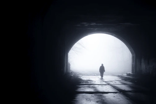 silhouette of person walking out from tunnel during daytime