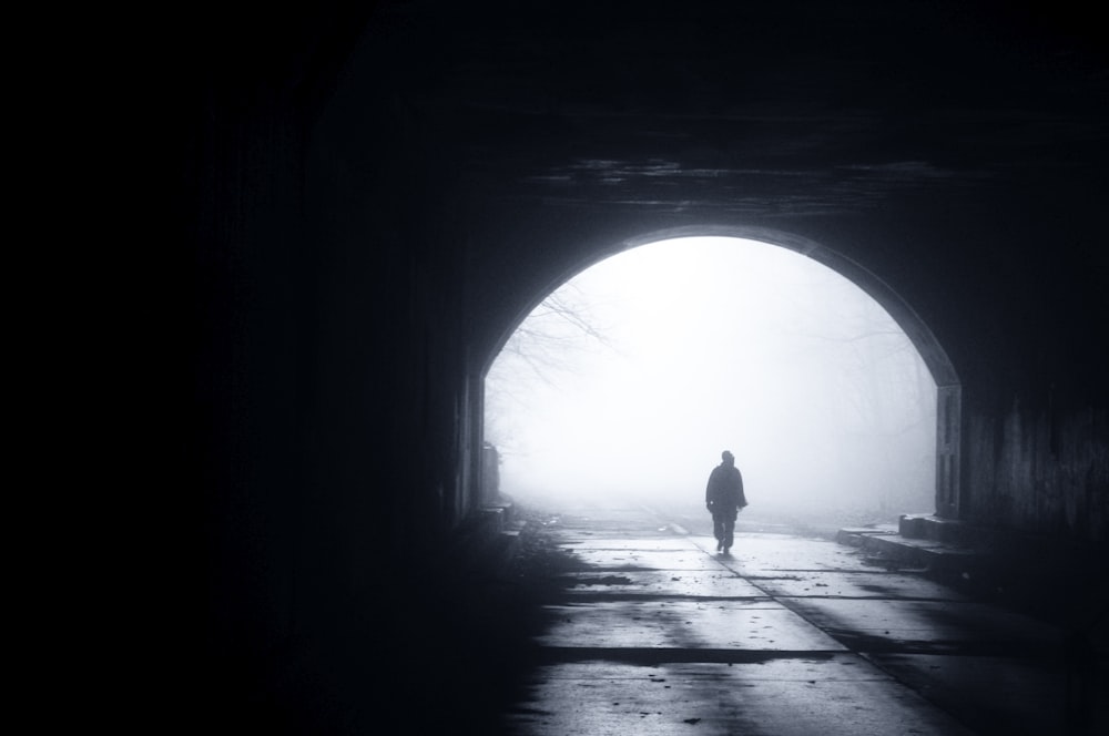 silhouette of person walking out from tunnel during daytime