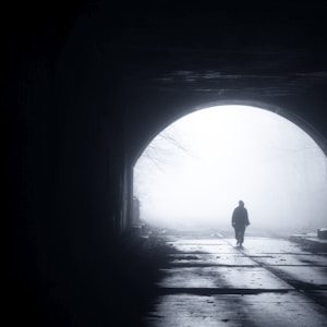 silhouette of person walking out from tunnel during daytime