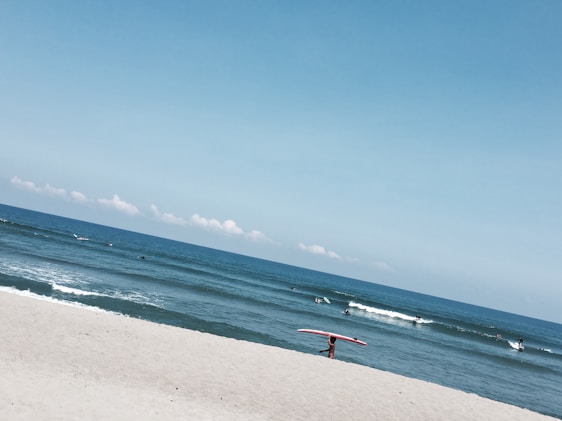 A vibrant beach scene with surfers wearing stylish lapartisil apparel catching waves under a clear blue sky.