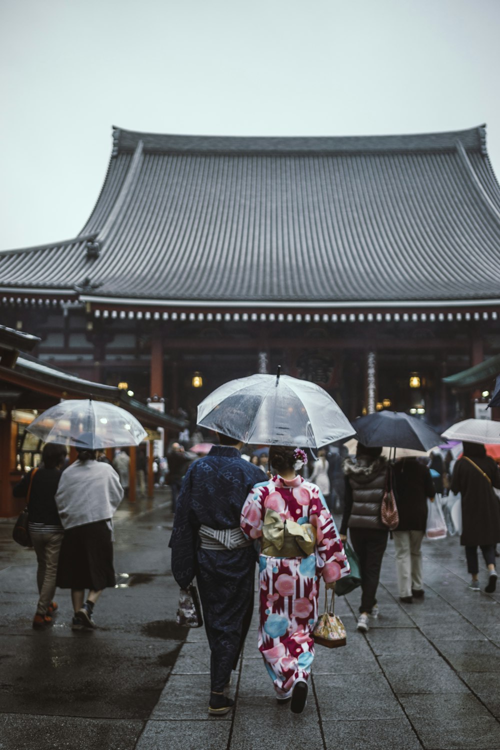 people walking on street while holding umbrellas going to pagoda