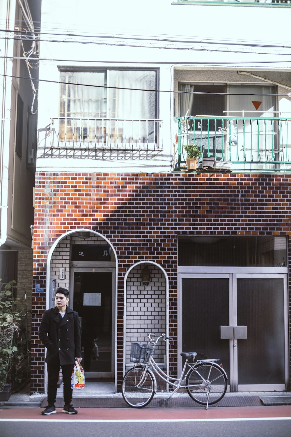 man wearing black jacket beside bicycle