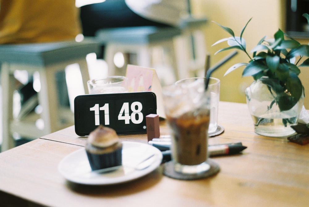 verre à boire clair à côté d’une assiette ronde en céramique blanche sur une table en bois brun