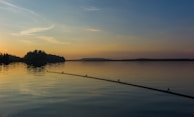 A sunset over a peaceful lake with fishing rods set up along the shore.