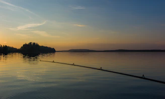 A serene southern lake at sunset with a small wooden dock and a fishing rod resting nearby.