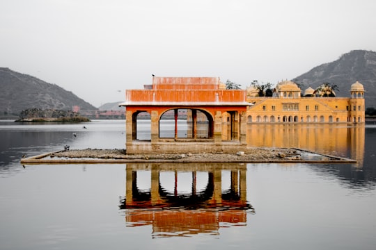 brown concrete building surrounded by water during daytime in Jal Mahal India