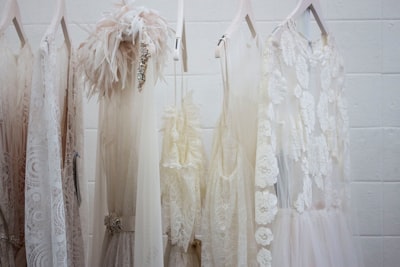 six women's white dresses hanging on hangers style zoom background