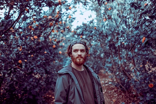 man wearing gray jacket standing near orange flowers in Bushy Park United Kingdom