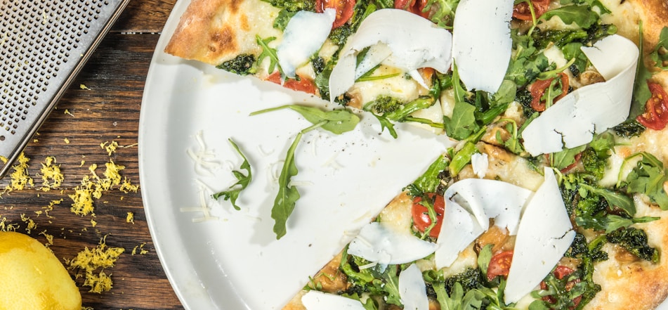 several sliced of vegetable pizza on round white platter