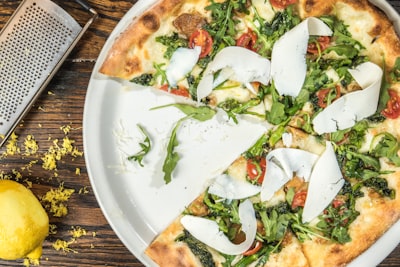 several sliced of vegetable pizza on round white platter dine teams background