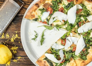 several sliced of vegetable pizza on round white platter