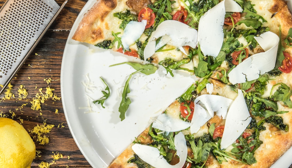 several sliced of vegetable pizza on round white platter