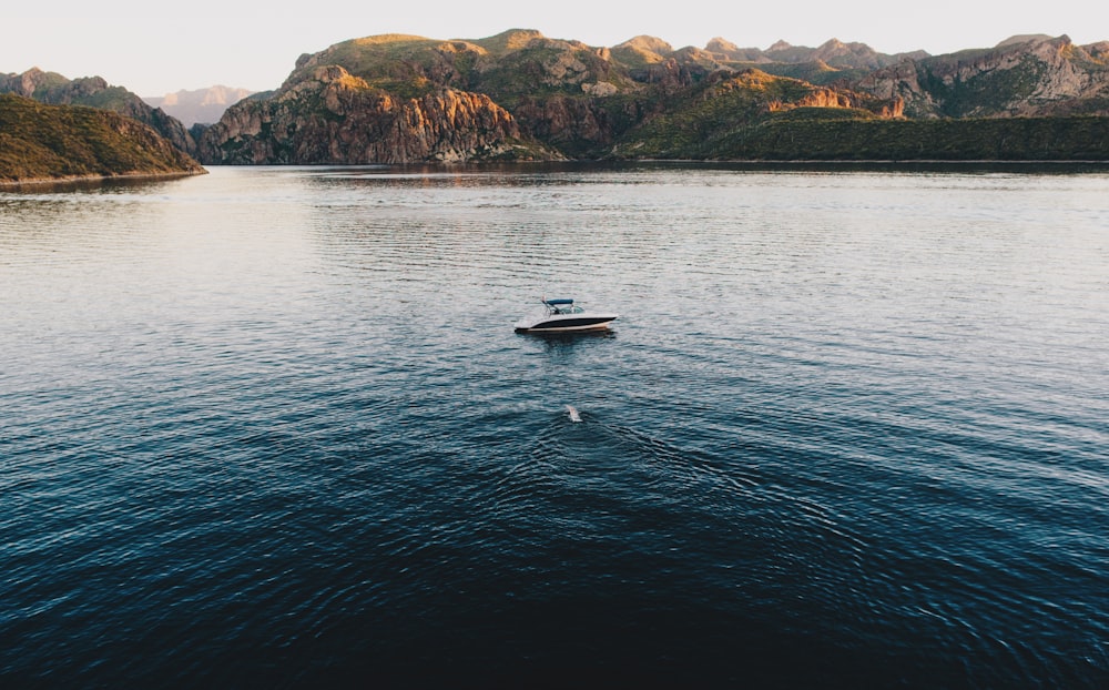 weißes und schwarzes Boot mitten im Wasser in der Nähe der Insel