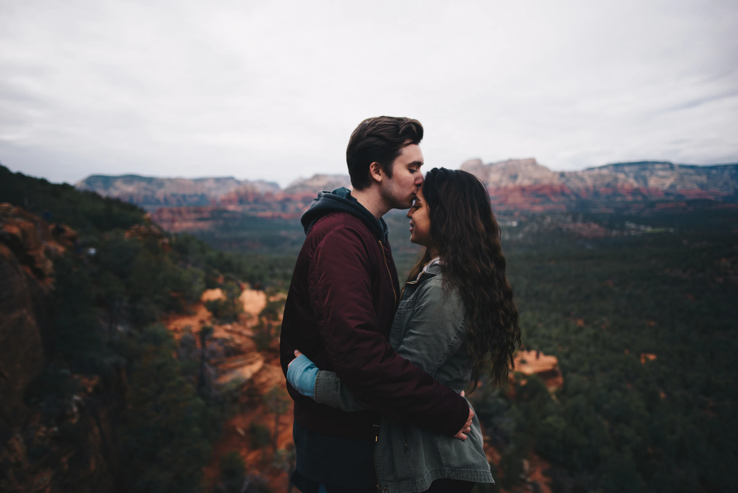 Man kissing a woman on the forehead in soft light