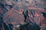 A traveler wearing functional gear overlooking a vast canyon landscape.