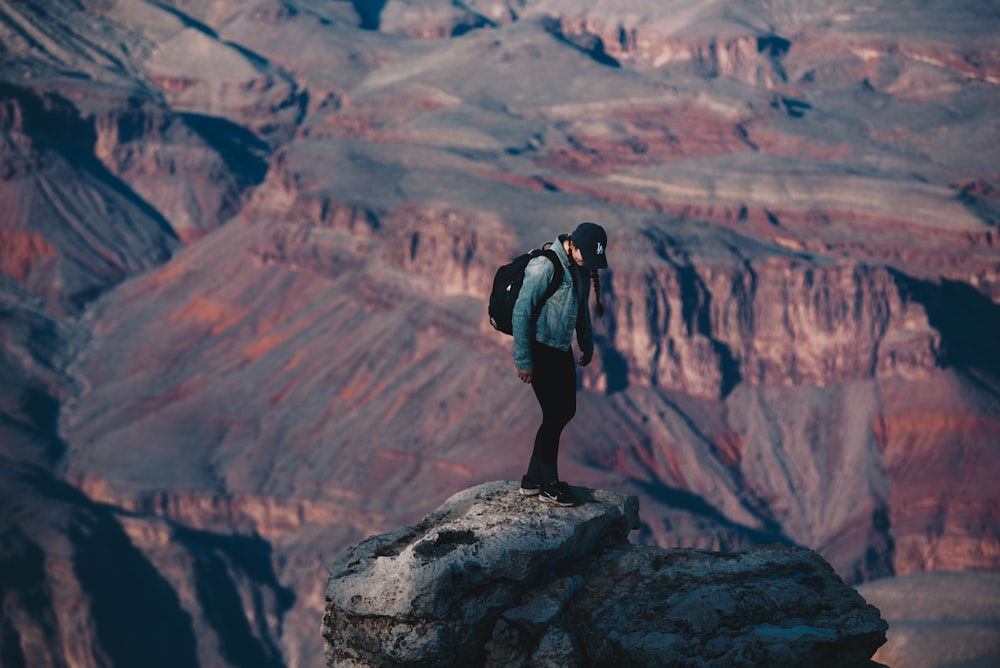Hombre de pie en el acantilado de la roca con vistas al cañón durante el día