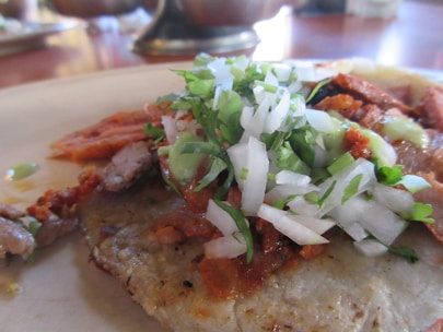 Close-up of a colorful taco with fresh ingredients on a rustic wooden table.
