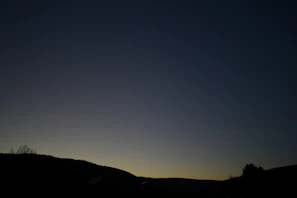 A quiet landscape at dusk with muted tones of dusk sky blending into gentle hills.