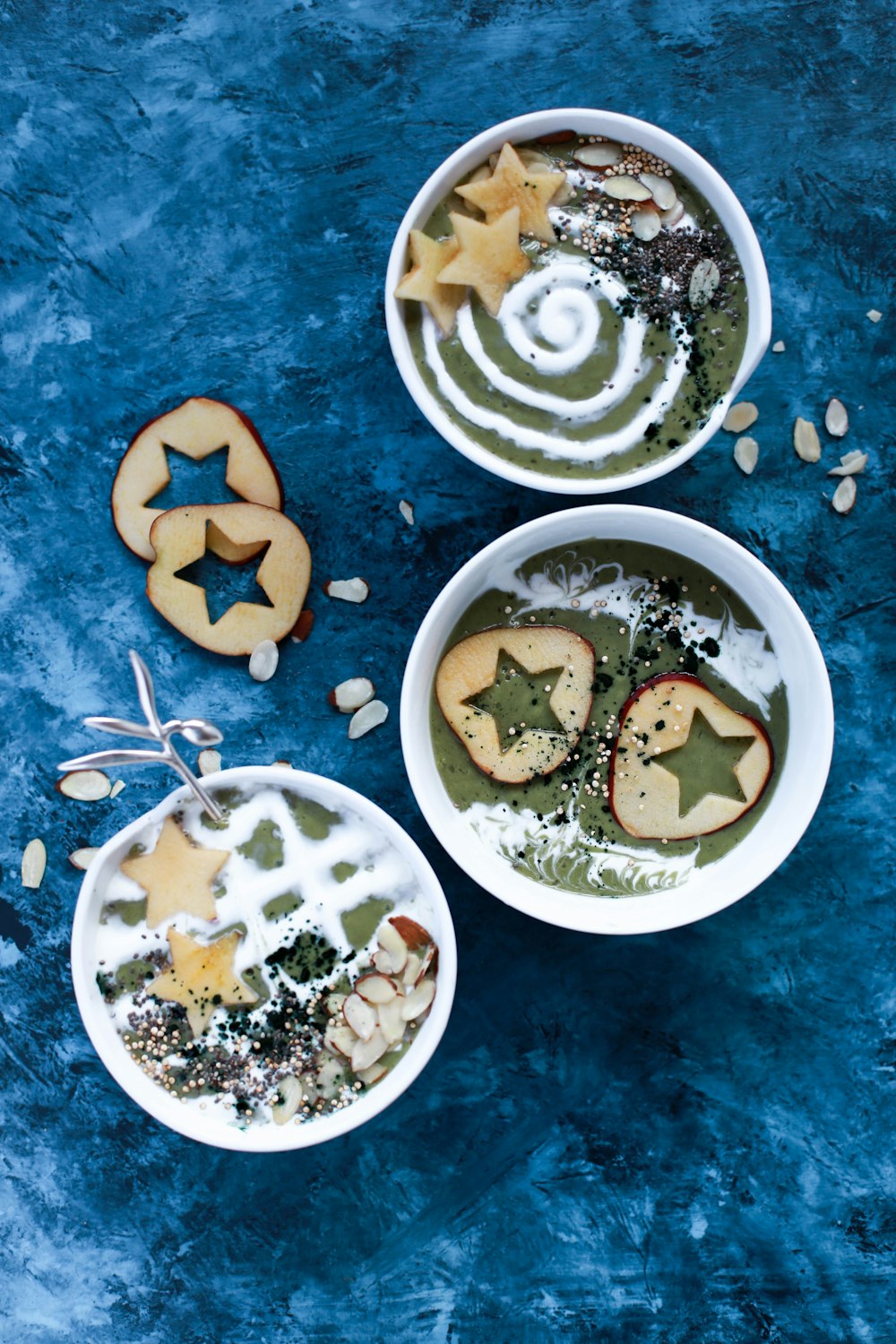 three white ceramic bowls with sliced apple and candy drizzle