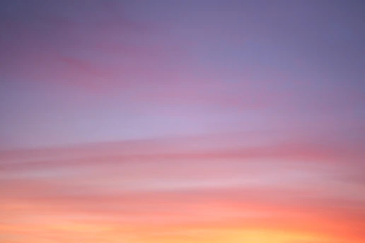 A serene sunrise sky blending soft lilac and lavender hues over a peaceful horizon.