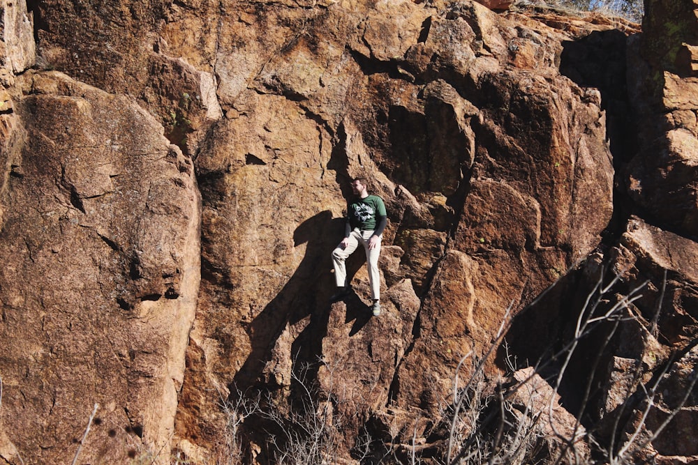 man in white shirt climbing brown rock mountain during daytime