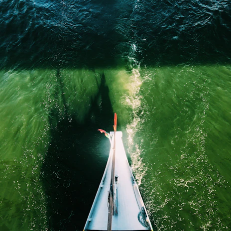Close-up of the boat’s sleek bow slicing through shimmering light blue sea with gentle ripples