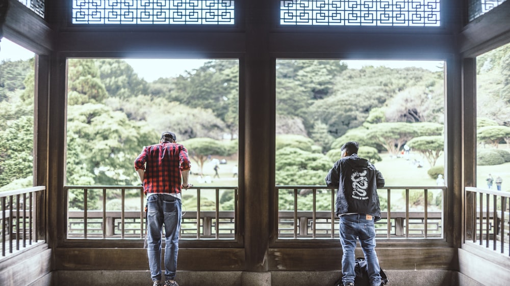 two men standing beside brown fence close-up photography