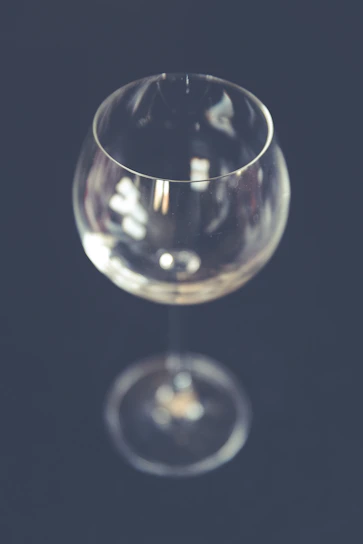 A sleek, minimalist wine glass catching soft light against a dark, elegant background.