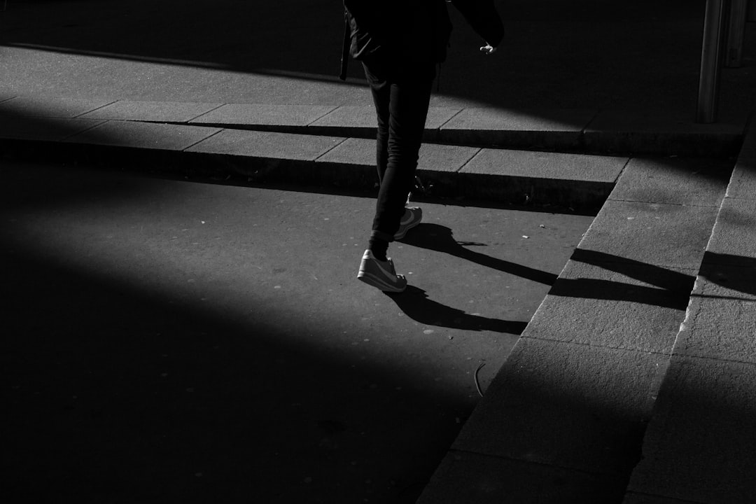 person wearing black pants and white shoes walking near gray concrete stairs