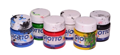 Six small paint jars arranged in two rows, each topped with a white lid. The jars contain an assortment of colors including blue, green, red, white, yellow, and black. Labels on the jars display the brand name 'GIOTTO DITA' and each jar shows signs of paint smears, suggesting frequent use.
