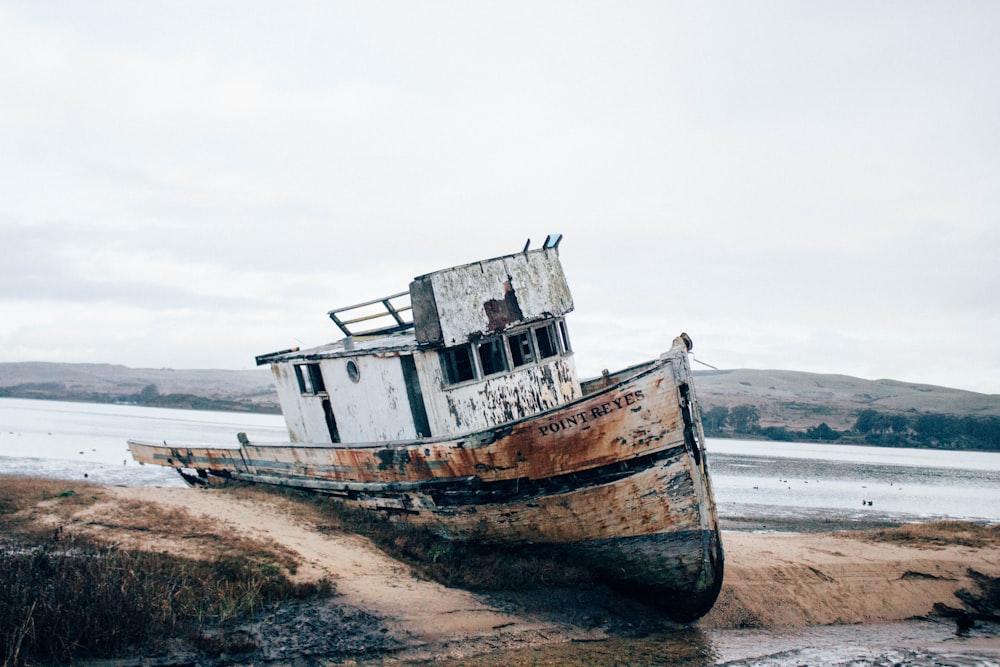 wrecked white and brown ship on sand