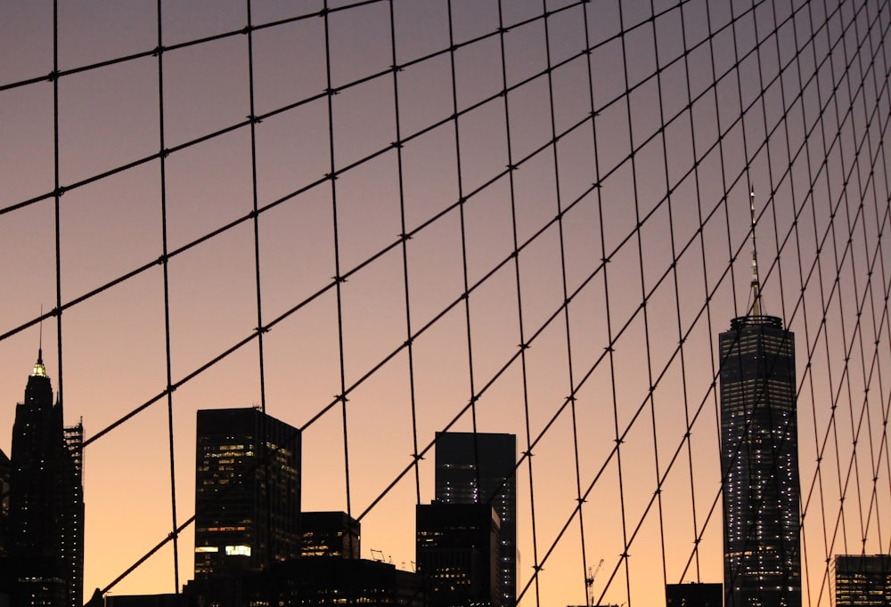 Looking up at the New York City skyline through a chain link fence at sunset
